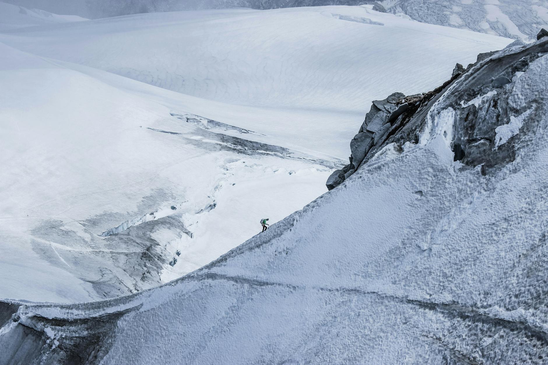 Hikers ascending steep mountain trail with backpacks and trekking poles against dramatic alpine scenery