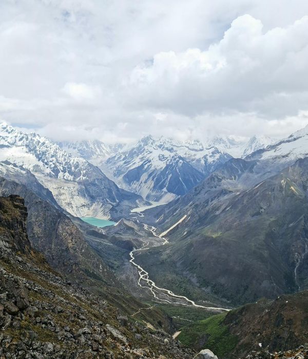 Majestic snow-capped mountain peaks rising above pristine alpine valleys under dramatic sky