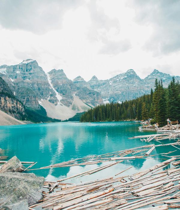 Pristine turquoise alpine lake surrounded by dense pine forests and snow-capped peaks